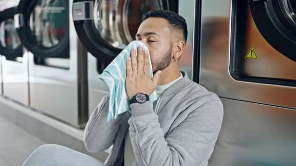 Young Hispanic Man Smelling Cloth Sitting Floor Laundry Facility — Stock Video