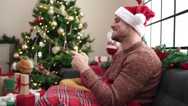 Mladý Běloch Pomocí Smartphone Sedí Pohovce Vánočního Stromku Doma — Stock video