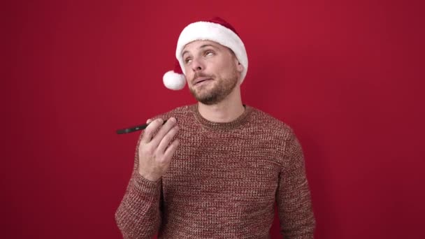 Junger Kaukasischer Mann Sendet Sprachnachricht Mit Weihnachtsmütze Über Isoliertem Rotem — Stockvideo