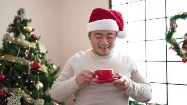 Młody Chińczyk Pije Kawę Stojąc Przy Choince Domu — Wideo stockowe