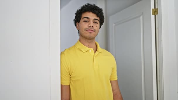 Mladý Latinsky Muž Usmívá Sebevědomě Pozdravit Rukou Doma — Stock video