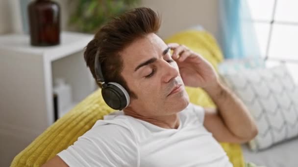 Joven Hispano Escuchando Música Sentado Sofá Casa — Vídeos de Stock