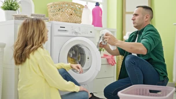 男男女女坐在地板上 在洗衣房里闻到脏衣服的味道 — 图库视频影像