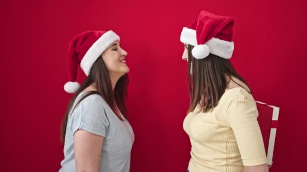 Dwie Kobiety Zaskakujące Prezentem Świątecznym Odizolowanym Czerwonym Tle — Wideo stockowe