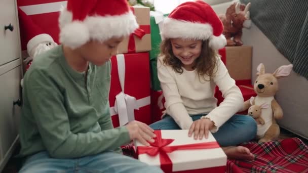 愛らしい男の子と少女は自宅で驚きの表現でクリスマスプレゼントをアンパック — ストック動画