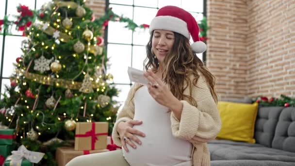 自宅で赤ちゃんの超音波を見ているクリスマスを祝う若い妊婦 — ストック動画