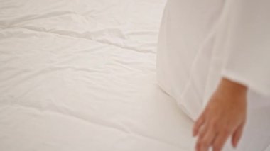 Genç sarışın kadın yatak odasında oturuyor.