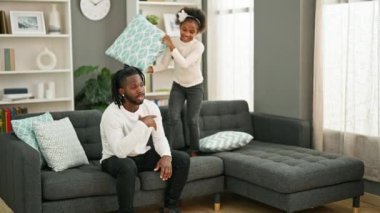 Afro-Amerikan baba ve kızı evdeki rahatsızlıktan dolayı stresli bir şekilde kanepede oturuyor.