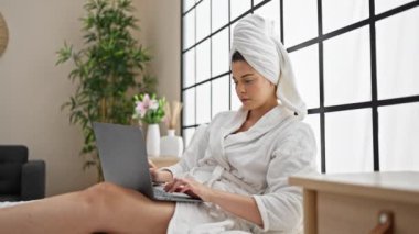 Yatak odasında dizüstü bilgisayar kullanan güzel İspanyol bir kadın.