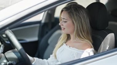 Sokakta kendine güvenen genç sarışın kadın gülümsüyor.