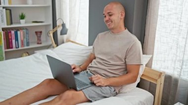 Genç İspanyol, yatak odasındaki yatakta dizüstü bilgisayarla video görüşmesi yapıyor.