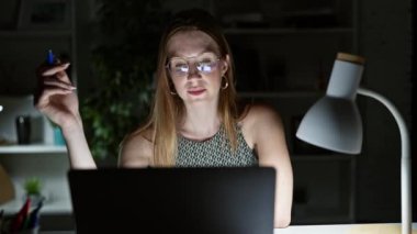 Genç sarışın iş kadını ofiste çalışırken laptop kullanıyor.