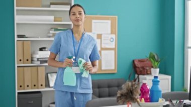 Afrika kökenli Amerikalı profesyonel temizlikçi elinde sprey ve ofiste gülümseyen bez tutuyordu.