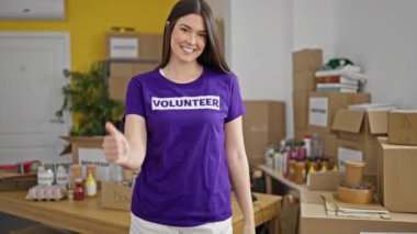 Genç ve güzel İspanyol kadın gönüllü gülümsüyor. Kendine güveni tam. Yardım merkezinde el hareketi yapıyor.