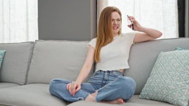 Genç sarışın kadın akıllı telefonda konuşuyor. Kanepede oturup tartışıyor.