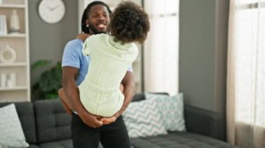 Afro-Amerikan baba ve kızı gülümsüyor kendilerine güveniyorlar evde birbirlerine sarılıyorlar