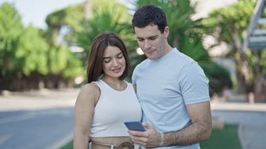 Gülümseyen güzel çift parkta akıllı telefondan özçekim yapıyor.