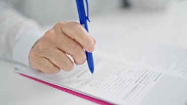 Orta yaşlı bir kadın ofiste belge imzalıyor.