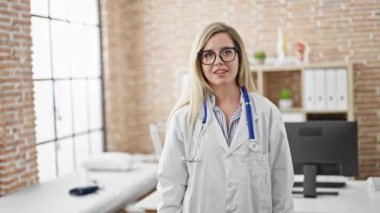 Genç sarışın doktor gülümsüyor. Klinikte kendine güveni tam.