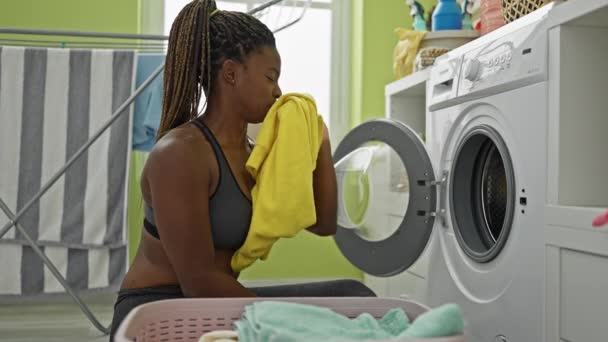 非洲裔美国妇女在洗衣房洗衣服时闻到脏T恤的味道 — 图库视频影像