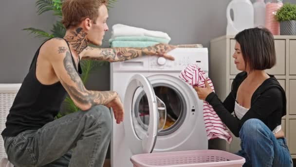 在洗衣房 一对漂亮的夫妇坐在地板上笑着洗衣服 — 图库视频影像