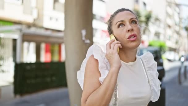 若い金髪の女性がストリートで深刻な表現でスマートフォンで主張 — ストック動画