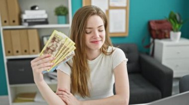 Genç sarışın iş kadını elinde Hungary Forint banknotlarıyla ofiste düşünüyor.