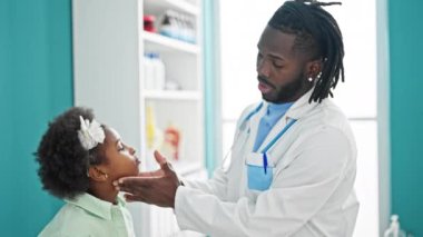 Doktor ve hasta klinikte boğazlarını muayene ediyorlar.