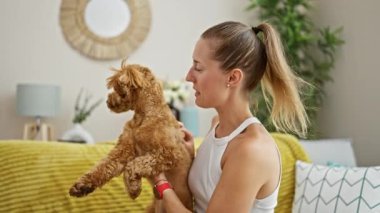 Köpekli beyaz bir kadın evdeki kanepede oturuyor.