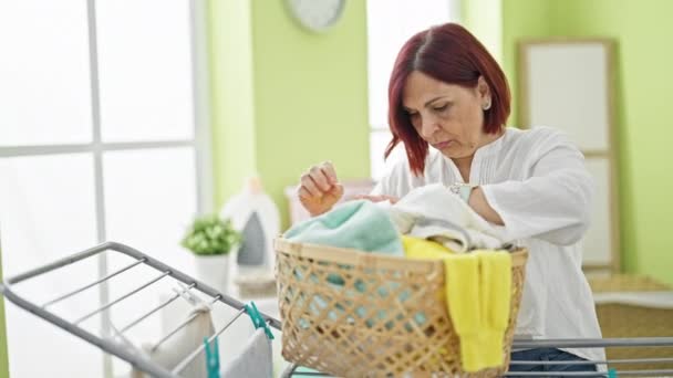 洗濯室でバスケットの服を探している中年の女性 — ストック動画