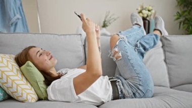 Genç kadın evde koltukta yalan smartphone kullanarak