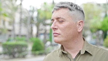 Sokakta ciddi bir ifadeyle duran beyaz bir genç.