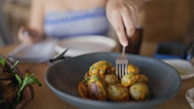 Genç İspanyol kadın restoranda patates yiyor.