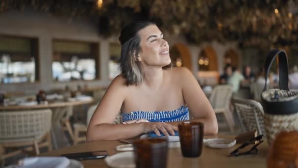Νεαρή Ισπανίδα Που Χαμογελάει Κοιτώντας Στο Τραπέζι Του Εστιατορίου — Αρχείο Βίντεο