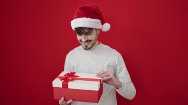 Gri arka planı kırmızı olan Noel Baba şapkalı genç adam.