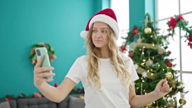 Akıllı telefonlu genç sarışın kadın Noel 'i evde kutluyor.