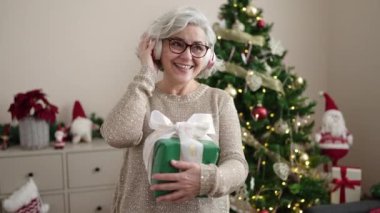 Noel ağacının yanındaki hediye kutusunu açan kadın. 