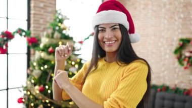 Noel Baba şapkalı güzel genç bir kadın Noel 'i evde kutluyor ve dans ediyor. 