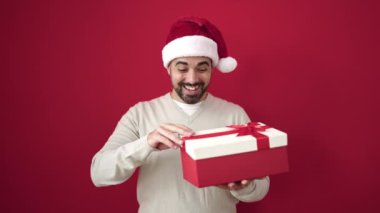 Kırmızı Noel Baba şapkalı genç adam ve kırmızı arka planda kırmızı hediye kutuları ve fotokopi alanı. Noel ve yeni yıl konsepti