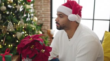 Genç yakışıklı adam, elinde kırmızı çiçeklerle Noel 'i evde kutluyor.