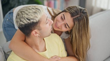 Güzel bir çift evdeki kanepede oturup birbirlerine sarılıyorlar.