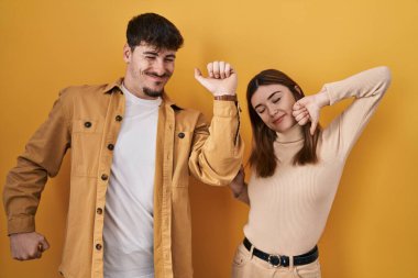 Sarı arka planda dikilen genç İspanyol çift yorgun ve rahat, uykulu ve sabahın erken saatleri için esniyorlar. 