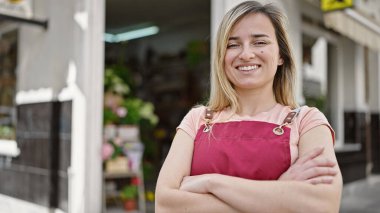 Sarışın, genç bir bayan garson. Kendine güvenen bir garson. Kahve dükkanının terasında kollarını kavuşturmuş duruyor.