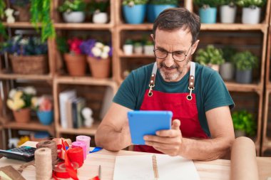 Çiçekçide dokunmatik ped kullanan orta yaşlı bir çiçekçi.