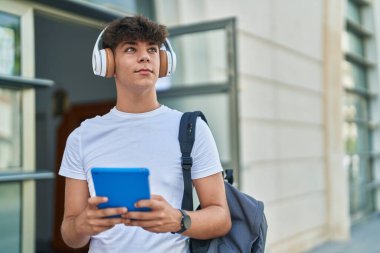 Latin kökenli genç bir öğrenci üniversitede müzik dinlerken touchpad kullanıyor.