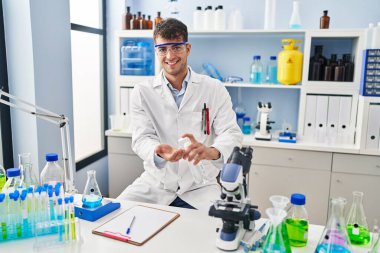 Genç İspanyol bilim adamı laboratuarda dezenfektan jel kullanıyor.