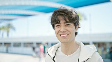 Parkta kendinden emin gülümseyen İspanyol genç adam.