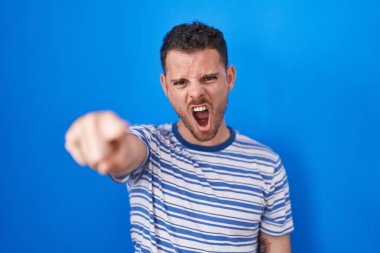 Mavi arka planda dikilen Latin asıllı genç adam kameraya kızgın ve sinirli olduğunu gösteriyor. 