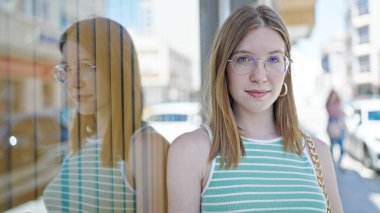 Sokakta ciddi bir ifadeyle duran genç sarışın kadın.