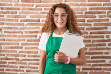 Yüzünde mutlu ve havalı bir gülümsemeyle sanat defteri tutan beyaz bir kadın. şanslı kişi. 